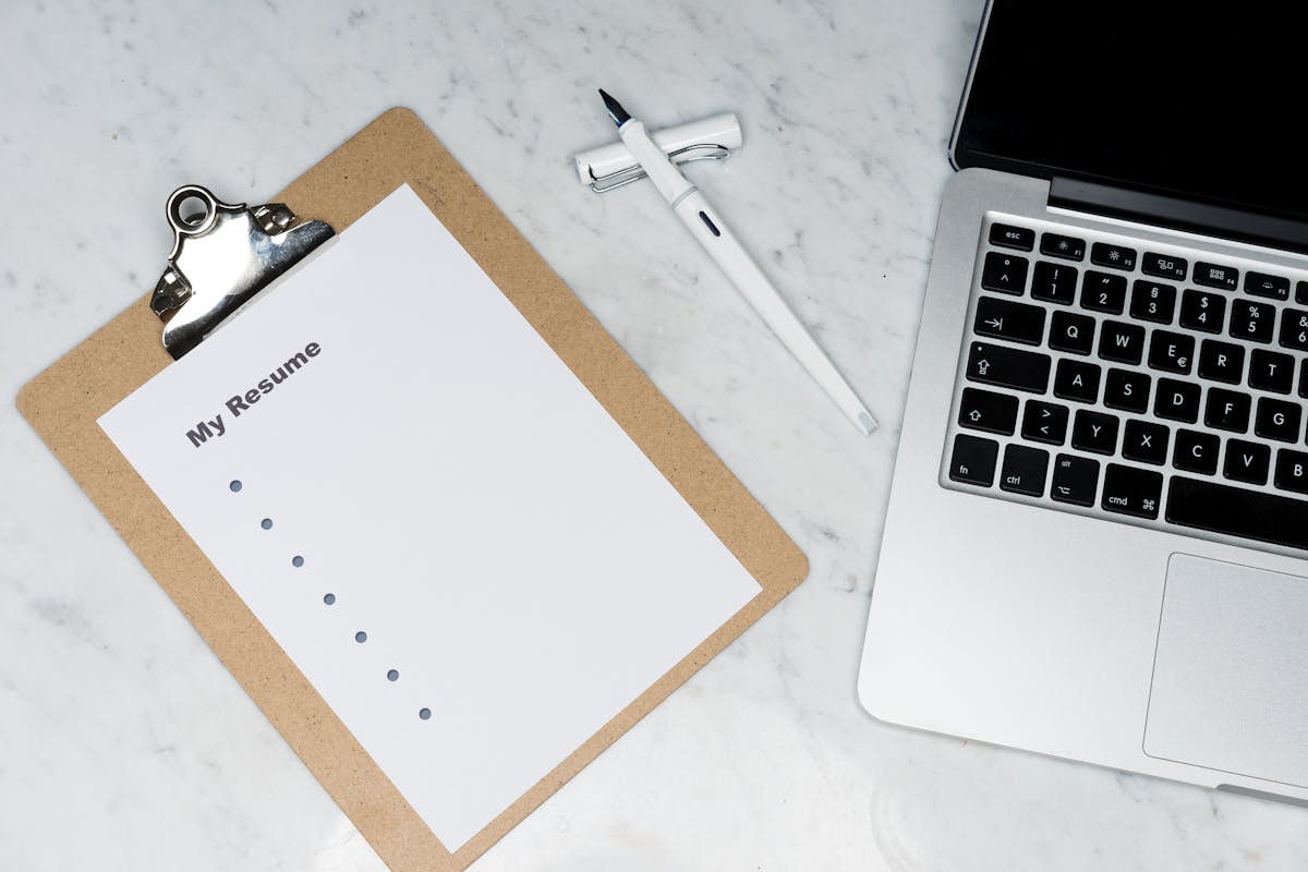 CV imprimé sur un clipboard à côté d'un ordinateur portable