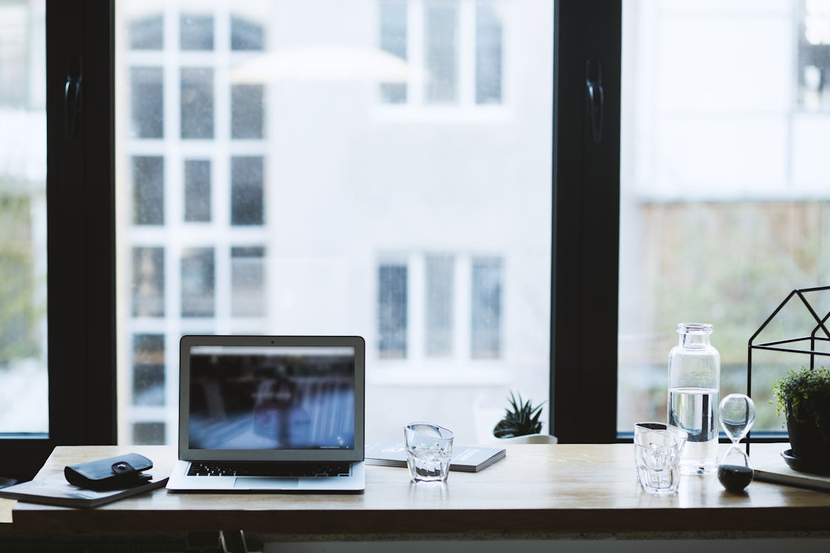 Bureau à domicile minimaliste avec ordinateur portable et verre d'eau