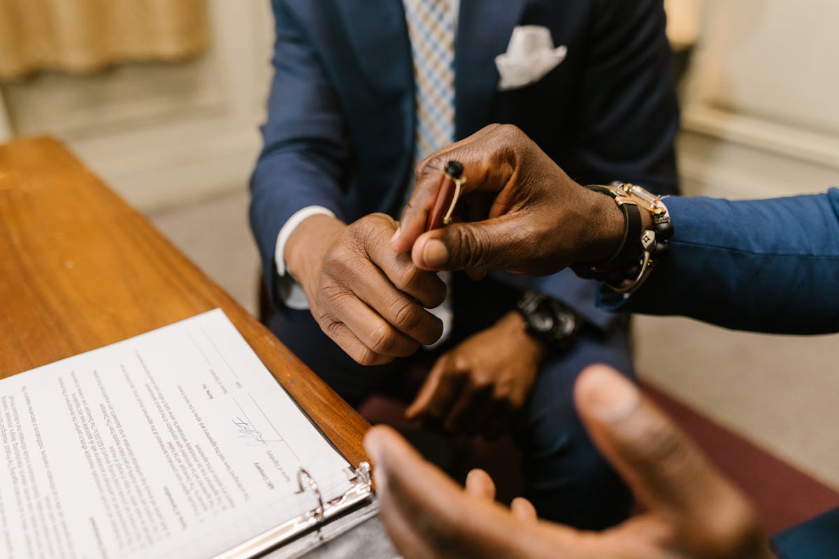 Two professionals exchanging a signed document across a desk