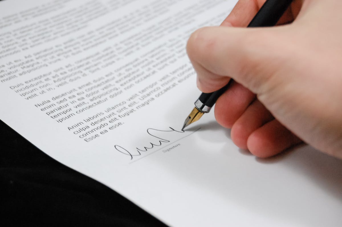 Person signing a formal contract with a fountain pen