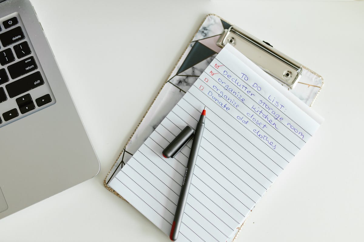 Liste de tâches soigneusement organisée sur un clipboard à côté d'un ordinateur portable